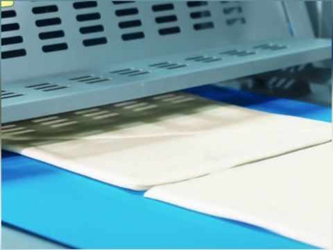 Heavy-duty pneumatic guillotine cutter segmenting the multi-layer laminated pastry dough block into precise sections.