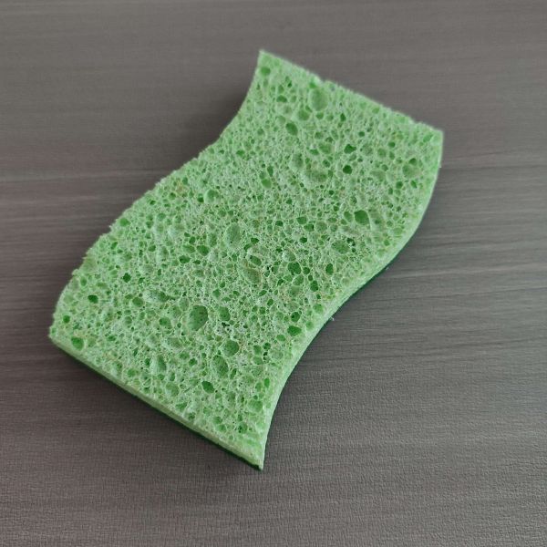 Green kitchen sponge scourer in use on cookware