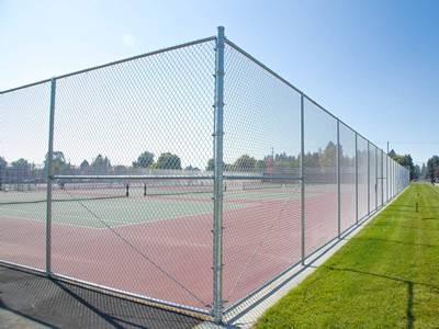 Polymer-coated tennis courts fence with double gates.